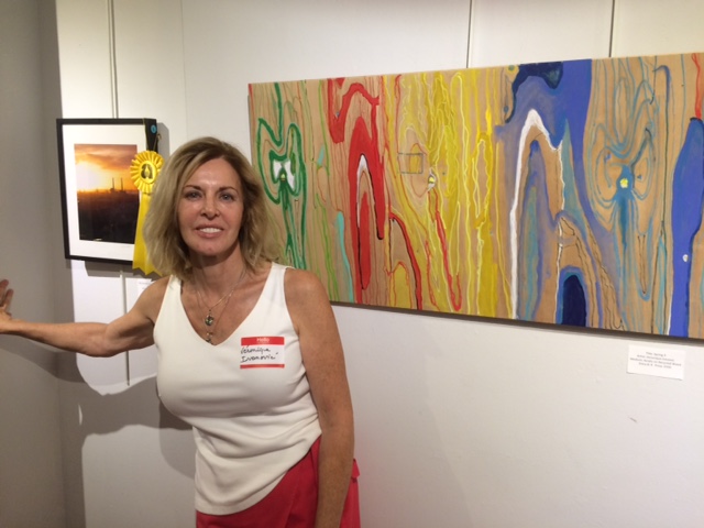 the artist between her award picture and one of her painting